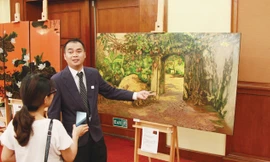 Giám tuyển Trần Quốc Hùng giới thiệu về các bức sơn mài sẽ được mang sang Hàn Quốc. Ảnh: N.M.Hà.