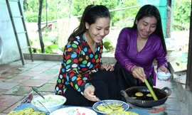 Nghệ nhân Lê Thị Bé Bảy (phải) hướng dẫn khách làm bánh. Ảnh: K. Mai.