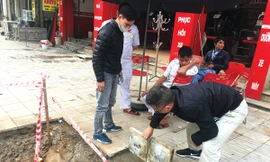 Đá lát trên vỉa hè tuyến phố Đền Lừ (Hoàng Mai) bị lật lên khá dễ dàng dưới sự chứng kiến của người dân. Ảnh: Trường Phong.