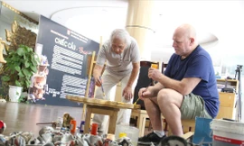 Nghệ sĩ Mark Cooper và họa sĩ Vũ Trọng Thuấn cùng nhau vẽ trên chất liệu gỗ chuẩn bị cho triển lãm “Chiếc cầu”. Ảnh: Thannh Trần 