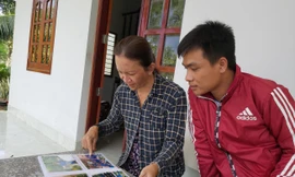  Bà Mai Thị Kim Chi lật giở từng trang album hình kỷ niệm với sinh viên tình nguyện. Ảnh: HÒA HỘI