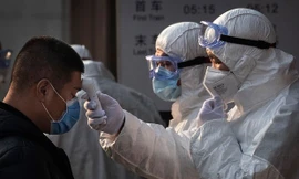 Nhân viên y tế Trung Quốc kiểm tra thân nhiệt một hành khách ở sân bay. (Nguồn: AP) 