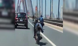 Thanh niên nằm trên yên điều khiển xe máy, phóng vun vút qua cầu Nhật Tân