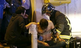 Lính cứu hoả Pháp hỗ trợ một người bị thương gần phòng hòa nhạc Bataclan. Ảnh: Reuters