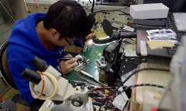 Một thợ sửa điện thoại tiến hành nâng cấp bộ nhớ trong iPhone. Nguồn: CCTV