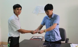 Anh Thành (trái) bàn giao chiếc vòng vàng cho chính quyền xã Cẩm Vịnh