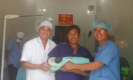 Bác sĩ, Đại úy Nguyễn Văn Phúc (người mặc áo xanh) cùng các đồng đội trực tiếp theo dõi, đỡ và đón cháu bé chào đời trên đảo. Ảnh: QĐND