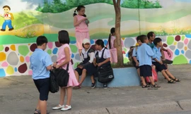 Học sinh chờ phụ huynh đến đón về. Ảnh: N.D