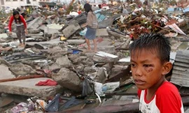 Em bé ngồi thẫn thờ giữa cảnh đổ nát hoang tàn sau siêu bão Hải Yến ở Philippines