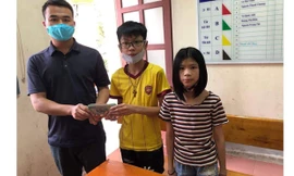 Em Hải (áo vàng ở giữa) trao lại số tiền nhặt được cho đại diện Công an phường Nam Hà.