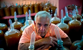 Ông Orestes Estevez bên những bình rượu nho đội bao cao su. ảnh: Ramon Espinosa