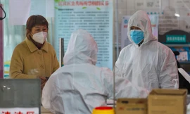 Nhân viên y tế tại một trạm y tế nói chuyện với một phụ nữ nghi nhiễm coronavirus ở Vũ Hán ngày 27/1. Ảnh: AP.