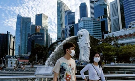 Hai thanh niên đeo khẩu trang đi ngang tượng ngư sư ở Singapore. Ảnh: AP.