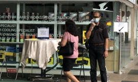 Nhân viên bảo vệ trung tâm thương mại Excelsior đeo khẩu trang, găng tay kiểm tra thân nhiệt mọi khách ra vào và hướng dẫn họ rửa tay bằng dung dịch sát khuẩn, đăng ký thông tin tại quầy trước cổng vào. Ảnh: Thái An.