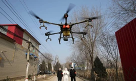 Một tình nguyện viên mặc đồ bảo hộ đang điều khiển drone phun thuốc sát khuẩn trong một ngôi làng ở tỉnh Hà Bắc ngày 31/1. Ảnh: China Daily.