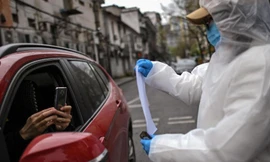 Một phụ nữ mặc đồ bảo hộ và đeo khâu trang giữ mã QR sức khỏe của thành phố Vũ Hán để cư dân quét trước khi vào khu dân cư trong thành phố. Ảnh: Getty.