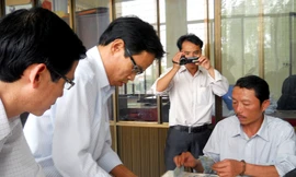 Cán bộ Ngân hàng Nhà nước kiểm tra số tiền bị cháy của tiểu thương Lương Hồng Thắng