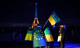 Người Ukraine cầm cờ Ukraine và châu Âu khi Tháp Eiffel được thắp sáng bằng màu cờ của Ukraine vào dịp tròn 3 năm nổ ra cuộc xung đột. (Ảnh: AP)