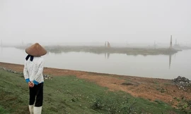 Một phụ nữ đứng trên đoạn đê mới được kè đá do bị sạt lở trên địa bàn xã Quế Tân (Quế Võ, Bắc Ninh). Ảnh: Trường Phong