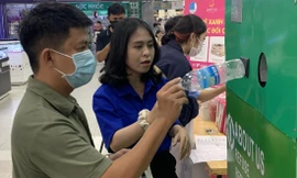 Đặng Nhật Uyên (sinh viên năm 4, Trường Đại học Nha Trang) hướng dẫn người dân sử dụng máy thu gom rác trong chương trình “Hè xanh mát, tích rác nhận quà” Ảnh: THỤC HIỀN