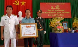 Bà Vân thay mặt gia đình đón nhận Bằng Tổ quốc ghi công cho con trai là liệt sĩ Lê Văn Tính ảnh: GĐCC