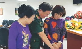 Anh hùng Phạm Tuân trao đổi với bà Nguyễn Minh Thủy (trái) về huy hiệu có chân dung Chủ tịch Hồ Chí Minh do cố hoạ sĩ Bùi Trang Chước vẽ Ảnh: KIẾN NGHĨA 