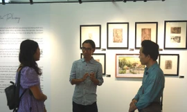 Họa sĩ Đinh Quang Hải (giữa) trao đổi với phóng viên báo chí tại triển lãm tranh “Hồi sinh”