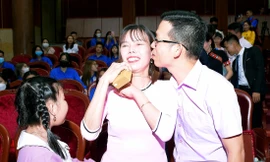 Anh Trần Mộng Hoàng (giáo viên ở Sóc Trăng) thể hiện cử chỉ yêu thương với vợ trong lễ tuyên dương "Gia đình trẻ Việt Nam tiêu biểu" năm 2022 Ảnh: Xuân Tùng 