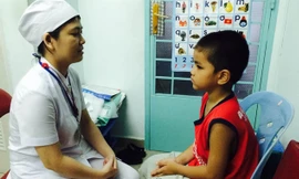 Bệnh nhi Trần V.T. đang được điều dưỡng Bùi Thị Duyên dạy cách phát âm. ảnh: L.N