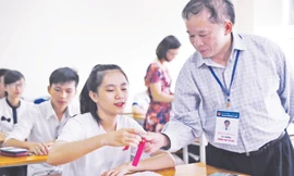 Thứ trưởng Bùi Văn Ga kiểm tra đồng hồ của một thí sinh ĐH Ngoại thương, sau đó chúc học sinh này thi tốt. Ảnh: Như Ý 