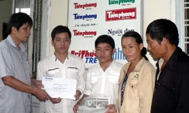 Đại diện báo Tiền Phong trao số tiền bạn đọc giúp đỡ cho hai anh em Danh - Thành với sự có mặt của ba mẹ hai em (ảnh chụp tháng 9/2009). ảnh: N.H