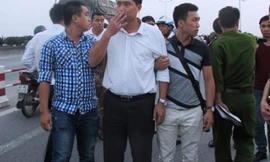 Bác sĩ Nguyễn Mạnh Tường (áo trắng) bị dẫn giải ra cầu Thanh Trì thực nghiệm hiện trường