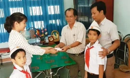 Hai em học sinh cùng lãnh đạo nhà trường bàn giao lại túi đựng vàng cho công an xã. Ảnh: X.V