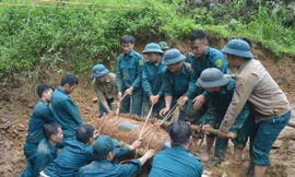 Chiến sỹ lực lượng vũ trang đưa bom xuống hố để hủy nổ. Ảnh: TTXVN phát.