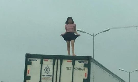 Người phụ nữ mặc váy ngắn, ca hát nhảy múa trên nóc thùng xe container.