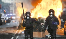 Cảnh sát chống bạo động đi ngang các thùng rác bị người biểu tình đốt ở thành phố Barcelona ngày 29-3 Ảnh: Getty Images