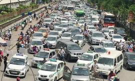 Đường Giải Phóng trước BV Bạch Mai ùn tắc nhưng taxi vẫn dàn hàng đứng đón, trả khách, còn công an có mặt (khoanh tròn) lấy báo che đầu Ảnh: A.Trọng