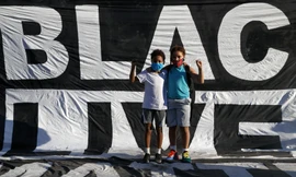 Hai cậu bé da màu đứng trước khẩu hiệu của người biểu tình căng ngoài công viên Lafayette ngày 7/6Ảnh: AP