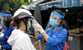 TNV kiểm tra thân nhiệt người dân tại một chốt chặn ở cổng chợ. Ảnh: Giang Thanh