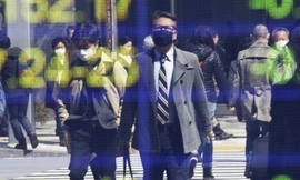 Hình ảnh người dân đeo khẩu trang được phản chiếu trên bảng điện tử của một công ty chứng khoán tại Tokyo ngày 18/3ảnh: AP