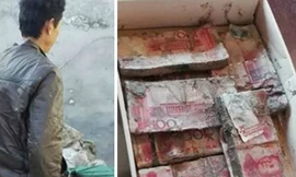 Ông Zhang đau đớn nhìn tiền bị mục, hỏng do mưa lũ. Ảnh: Dailynews.