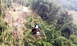 Cả người và xe đang đu ở độ cao hàng chục mét . Ảnh: FB Laocaionline.com. 