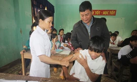 Thầy Nguyễn Khắc Điệp động viên học sinh tiêm văcxin bệnh bạch hầu. Ảnh: Đắc Thành.