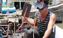 Út Nghĩa kiểm tra đồ nghề trước khi trao cho bạn lặn. Ảnh: Phúc Hưng