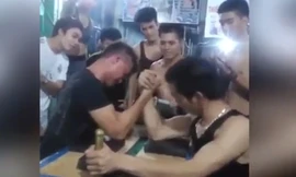 Mặt người đàn ông áo đen đỏ gay, anh đang gồng mình để kéo tay đối thủ về phía mình.