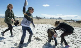 Trẻ em chơi đùa trên bãi biển Huntington trắng xóa sau trận mưa đá. 