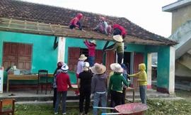 Sau bão, nữ giáo viên leo nóc nhà lợp ngói cho trường