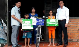 Đại diện báo Tiền Phong và Công ty Điện lực tỉnh Vĩnh Long trao quà cho em Lý Lam Chiều và em trai Lý Gia Trường.