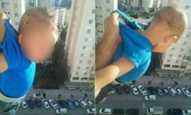 Bức ảnh bé trai bị người thân treo lơ lửng phía ngoài cửa sổ căn hộ trên tầng cao gây bức xúc dư luận Algeria. Ảnh: Facebook.