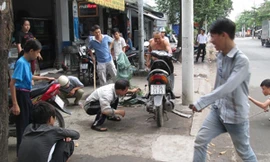 Nhiều người vây quanh xe máy để truy tìm con rắn.